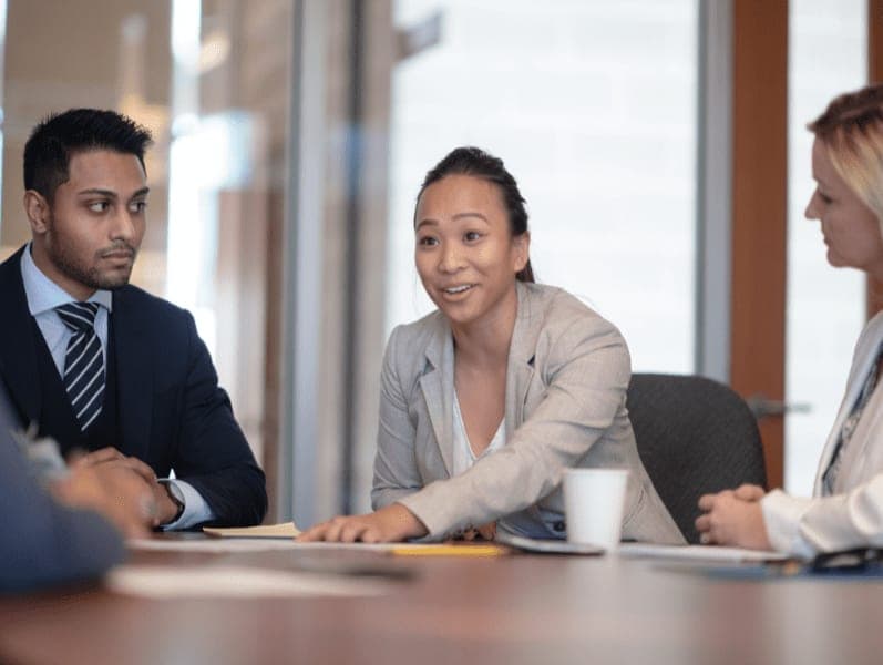 Female employee discussing report during meeting with colleagues.