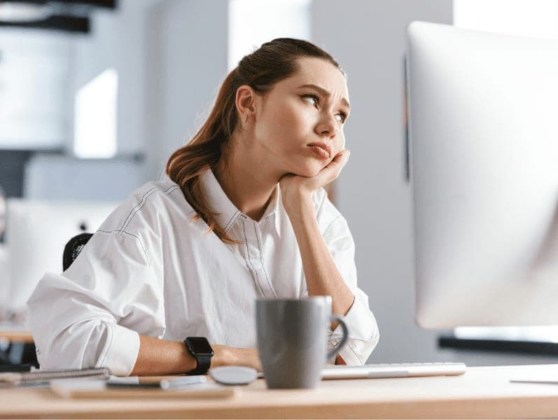 Bored young woman looking at computer in the office.