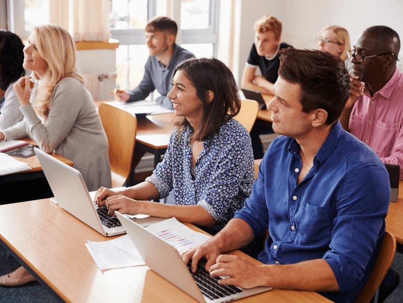 Mature students sitting at desks in class.