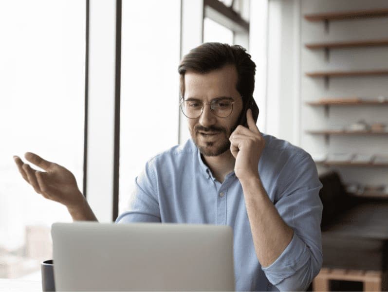 Businessman working on laptop while having a call with client.