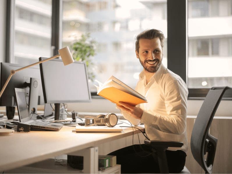 Male employee holding a book in the office.