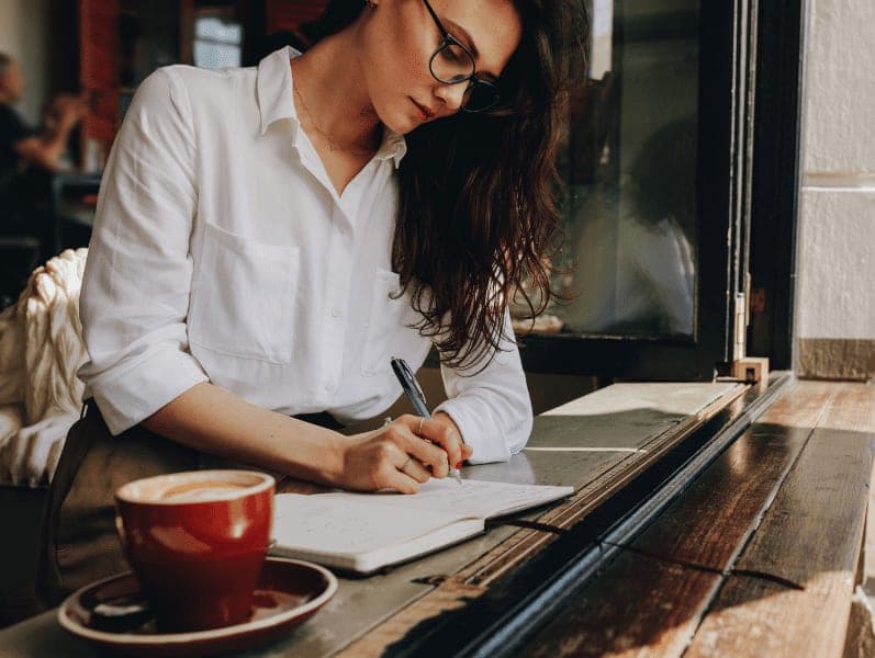 Woman taking notes in the cafe.