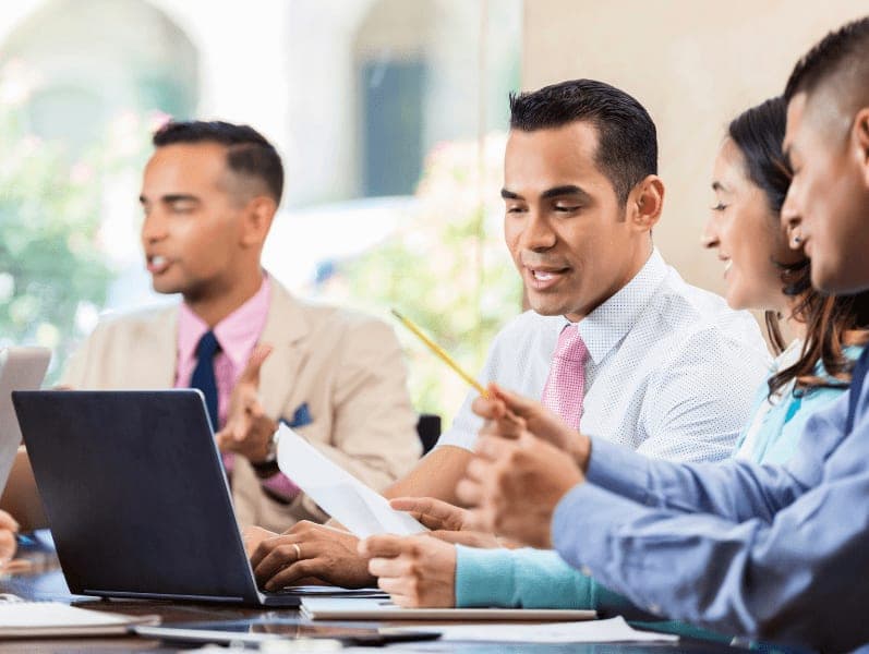 Hispanic business professionals talks during staff meeting.