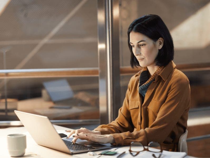 Businesswoman sitting at her workplace and typing on laptop.
