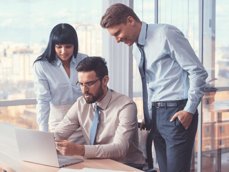 Three people having a discussion using laptop in the office.