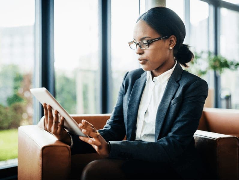 Female office employee sitting down working, using a digital tablet.