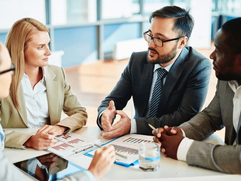 Serious businessman explaining principles of work to his colleagues at meeting.