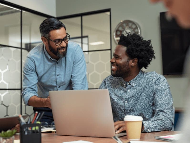 Two casual business partners sitting at table together and working.