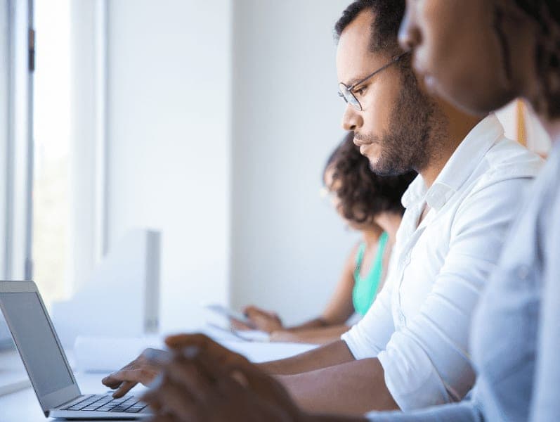 Male employee working in office among colleagues.