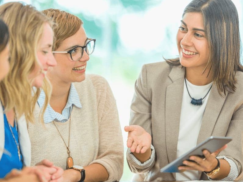 Female employee using a digital tablet explaining project to colleagues.