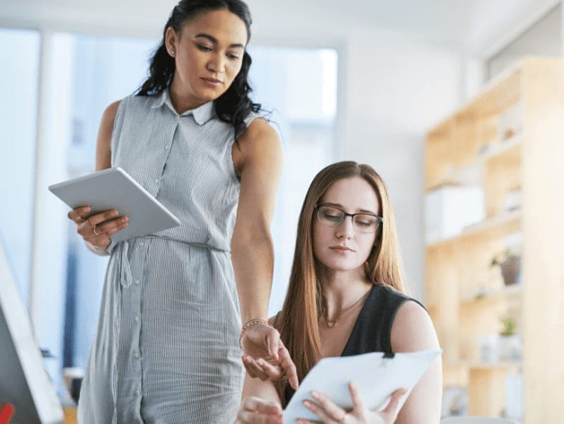 Two businesswomen going through paperwork together in an office.