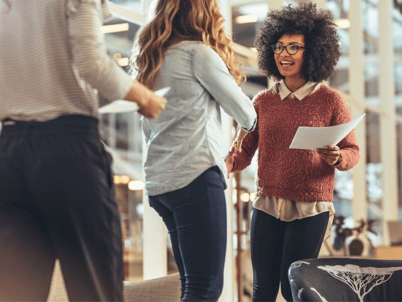 Woman entrepreneur holding papers, greeting a business client at work place.