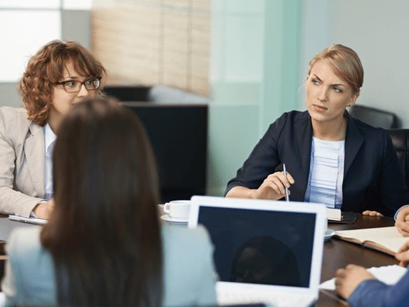 Serious female business leader listening to colleagues in meeting.