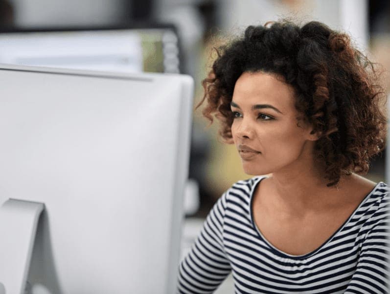 Serious businesswoman working at her desk, looking at her desktop computer.