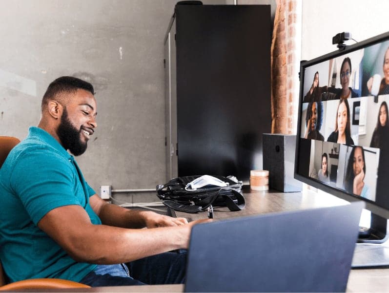 Businessman taking notes during a virtual meeting with his colleagues.