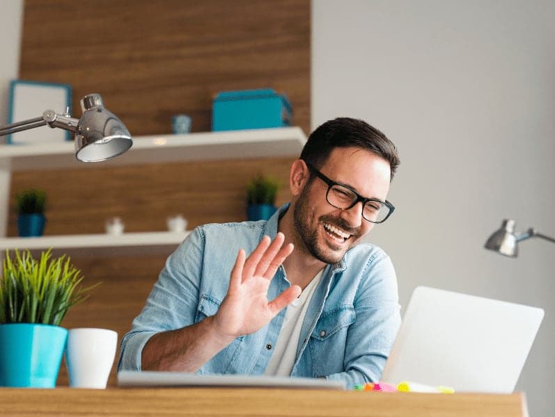 Smiling young man having video call and waving.