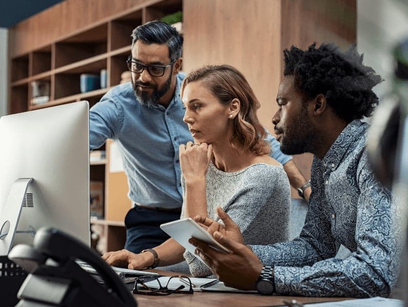 Three colleagues looking at the computer having a discussion.