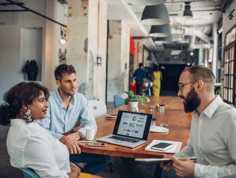 Three people in the conference room having a discussion.
