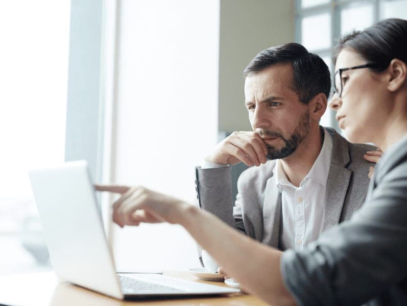 Two business people sitting having a discussion on the laptop.