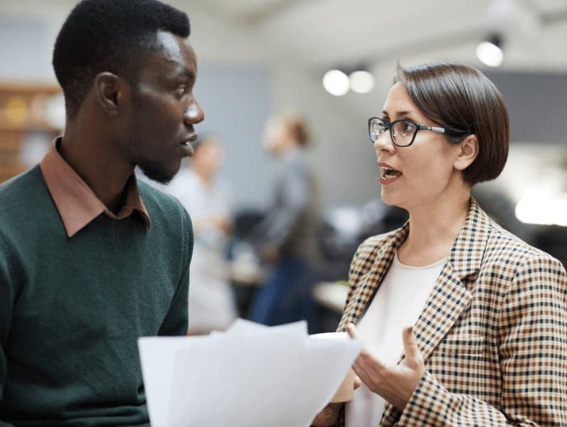 Female business manager talking to an African-American colleague while working in office 