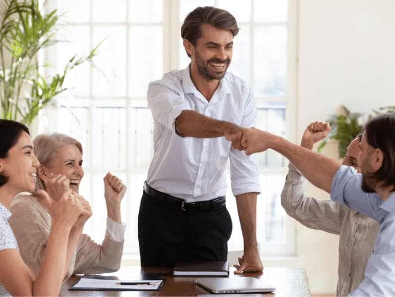Happy businessmen fist bumping at meeting table