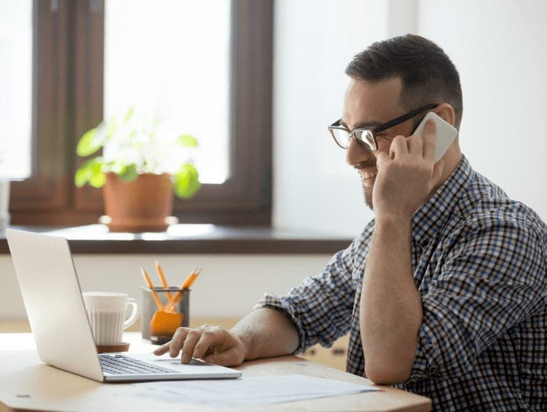 Smiling male worker speaking on phone consulting client online