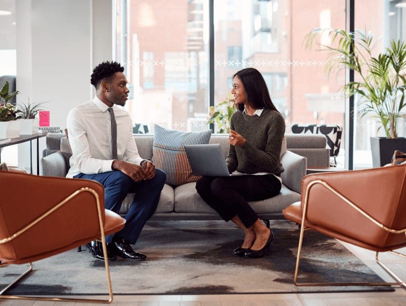 Businesswoman interviewing male job candidate in seating area of modern office