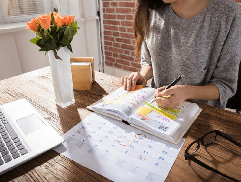 Woman sitting at a table outlining her schedule for the week to manage her team