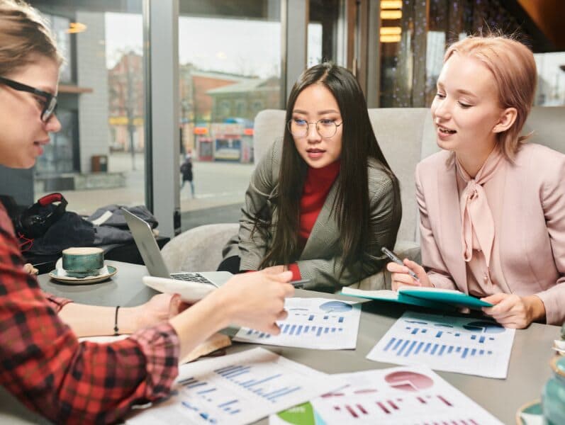 Three females' sitting around table reviewing documents