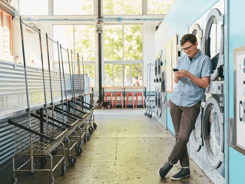 Young male leaning up against a wall on his phone