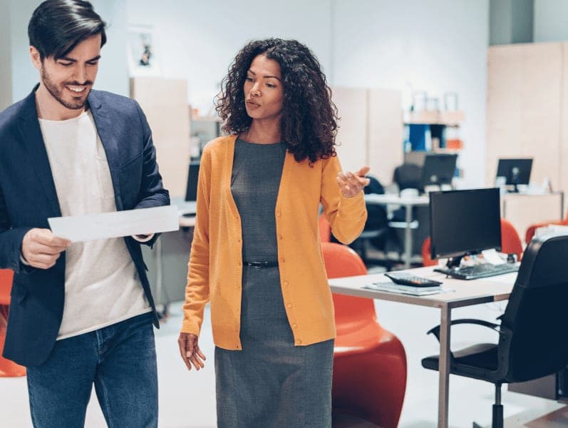 Two people standing while in discussion in the office.