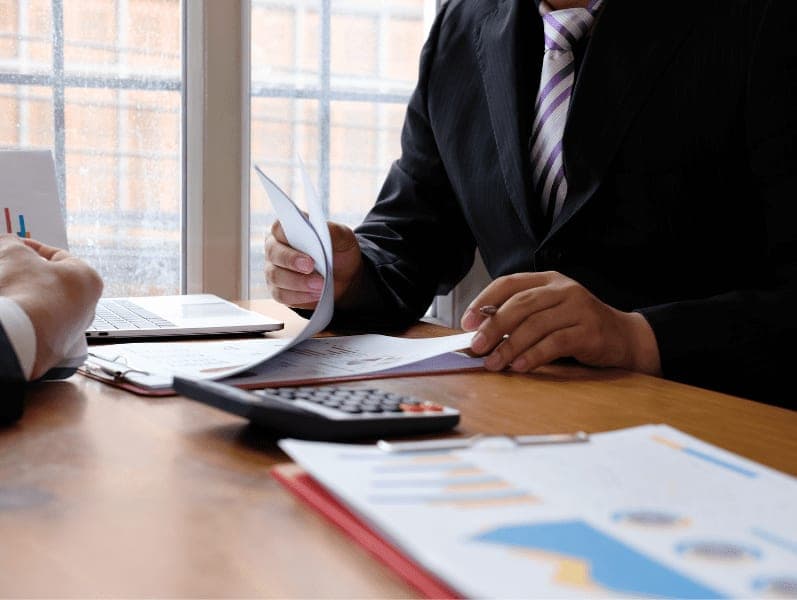 Businessman holding pen while reading documents.