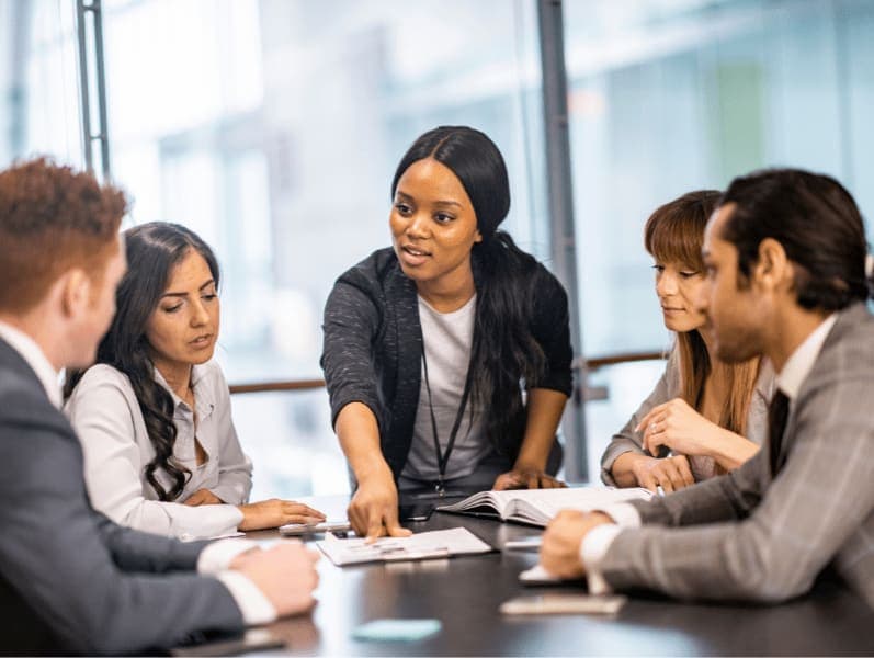 A group of adult business-people are having a meeting in an office room.