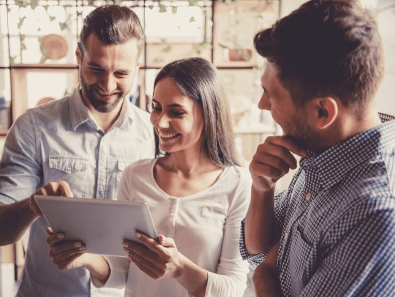 Business people are using a digital tablet, sharing ideas and smiling while working in office