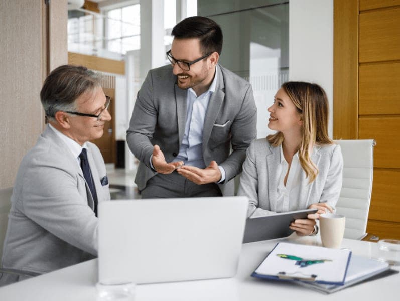 Younger male employee speaking with male and female colleagues out timesheets