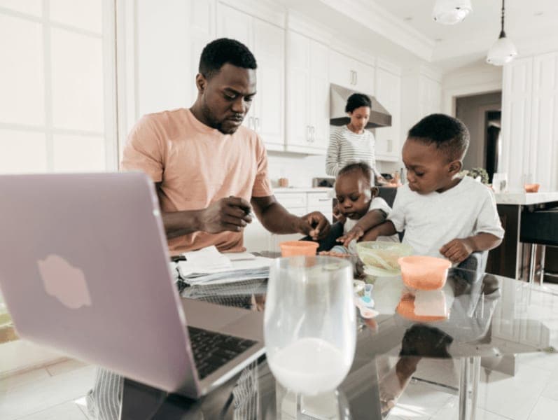 Man sitting at kitchen table with kids practicing his time management skills