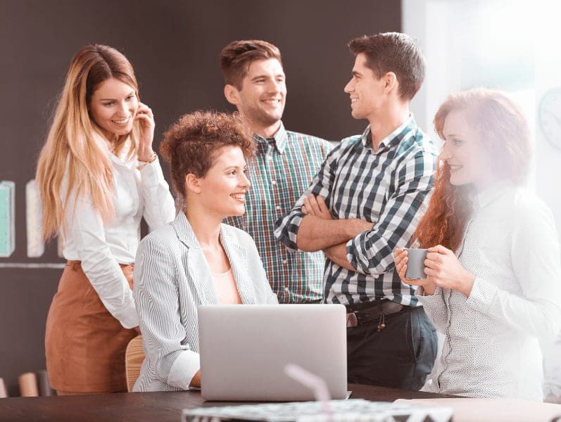 Team of employees gathered around laptop
