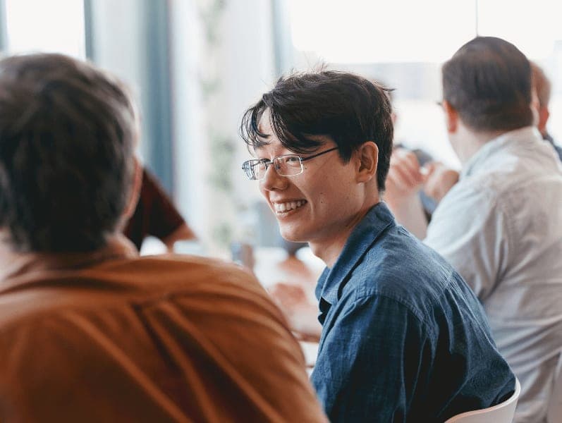 Male colleague with glasses looking to colleague at a table