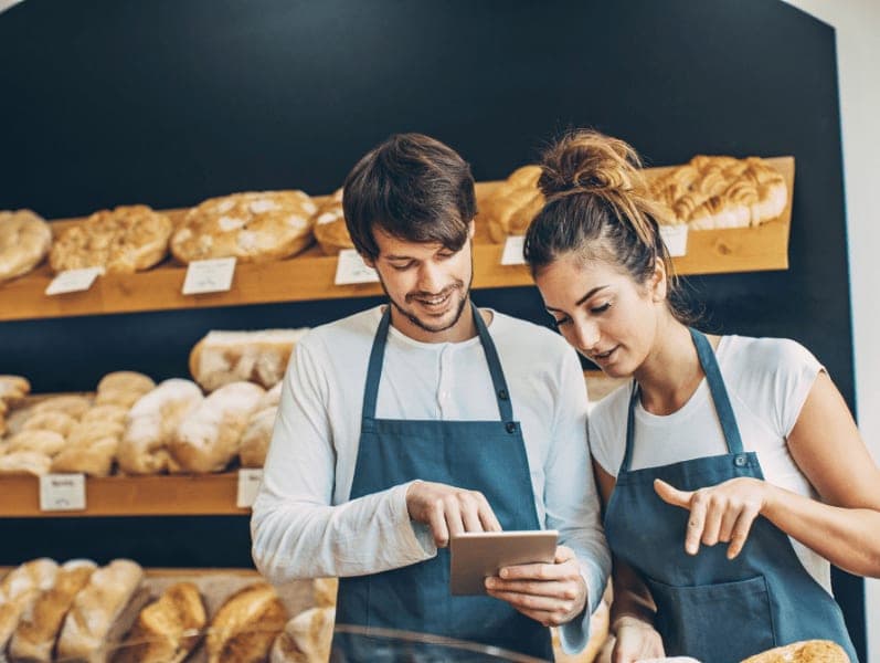 Male and female colleagues in bakery using a tablet to record something