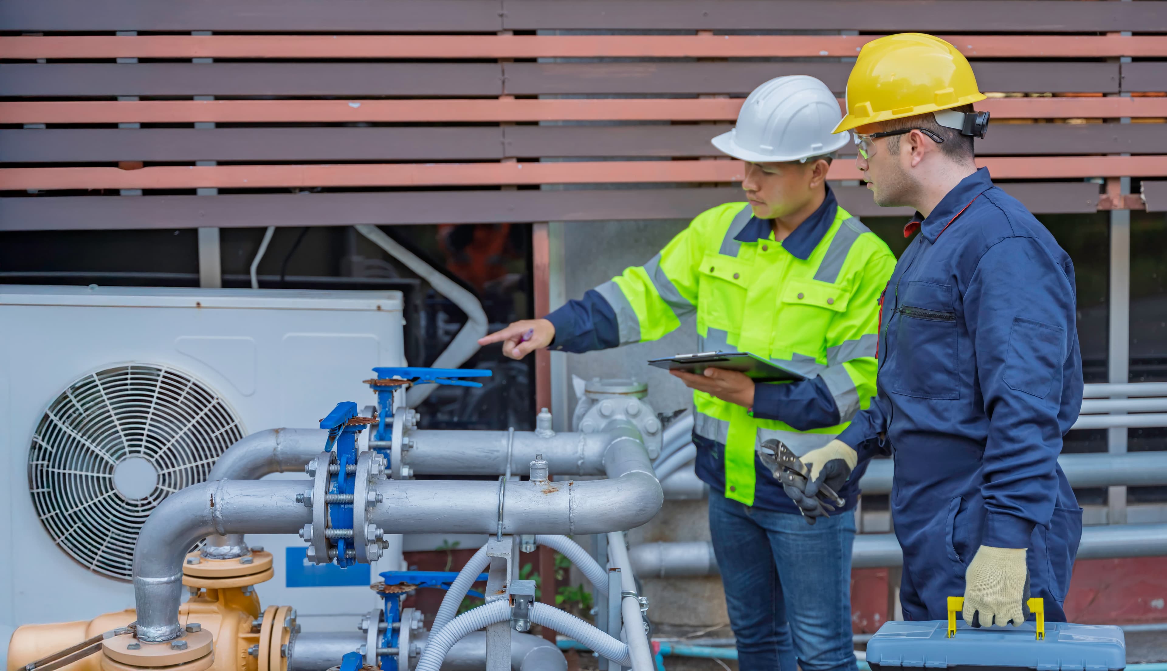 Two people in hard hats work on something