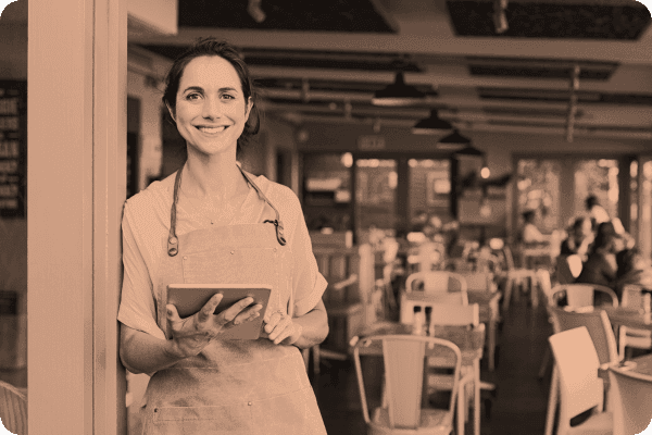 A solopreneur smiles while on her tablet outside of her business