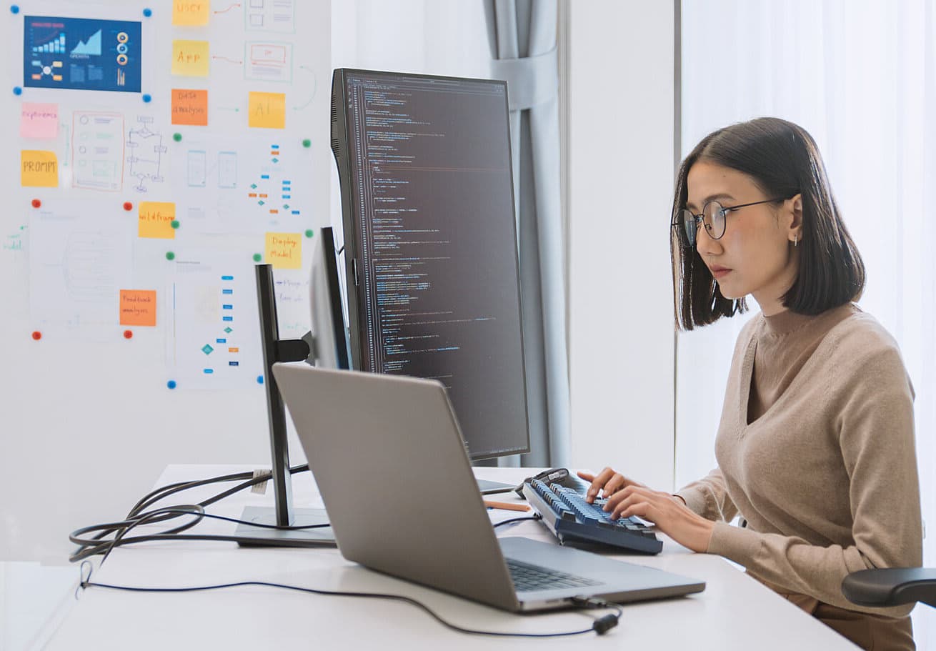 Young adult software developer coding on desktop computer