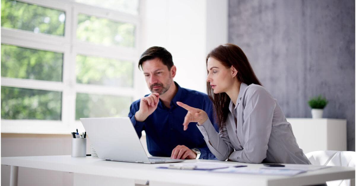 Two people work on a laptop