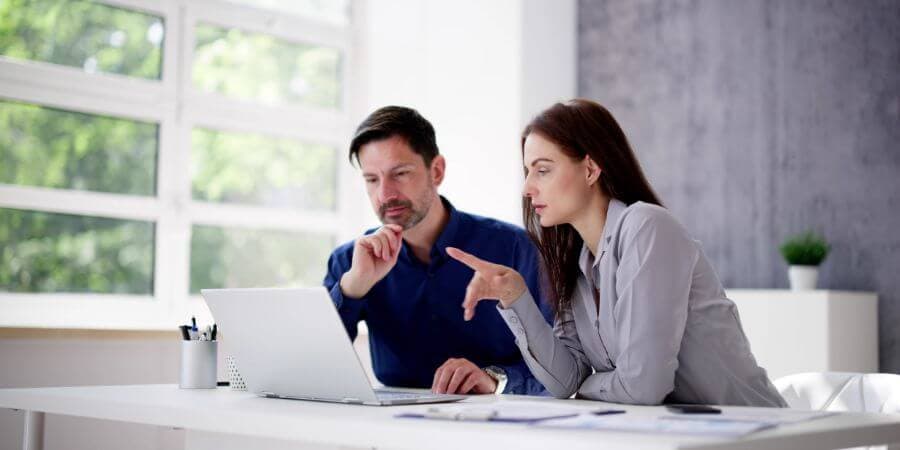 Two people work on a laptop