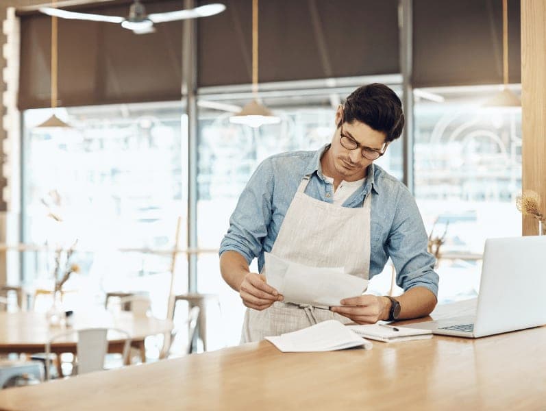 Man reviewing employees timesheets while in his coffee shop