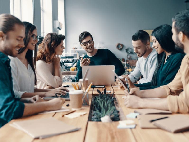 Marketing team sitting around a table reviewing items with smiles