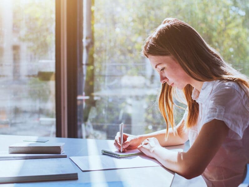 Woman Sitting at Desk with window beside her study for an exam