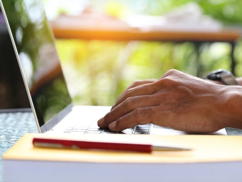 View of hands of male working away on a laptop in portrait view