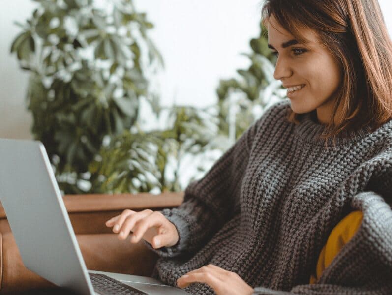 Female sitting on couch with a side view of her working on her laptop