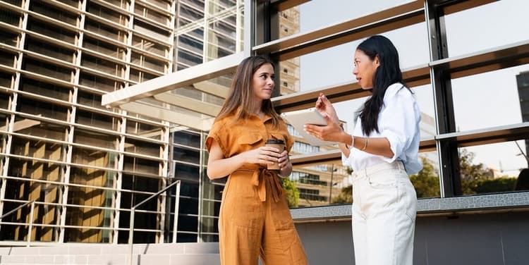 Two women talk in front of a building